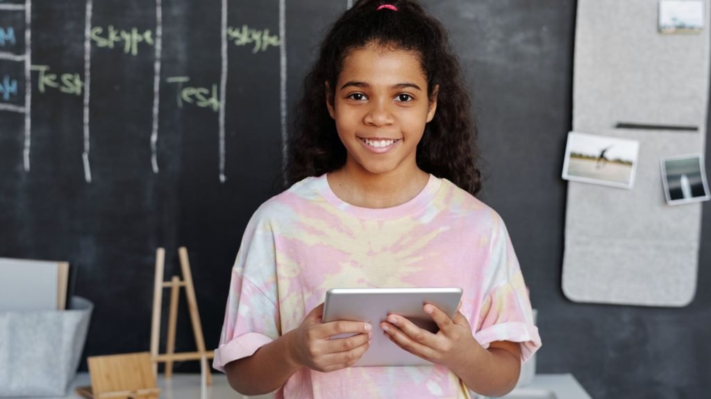 a girl smiling and playing educational video games on her tablet