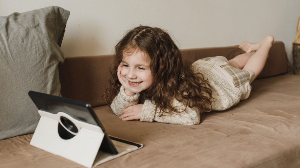 a young girl watching an educational show on her tablet